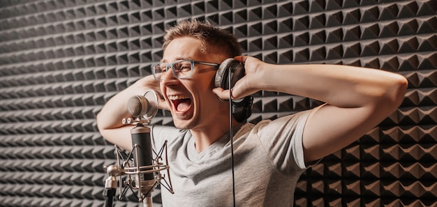 Der Sänger singt im Studio in ein Mikrofon. Mann mit Kopfhörer schreibt einen Podcast, ein Hörbuch. Künstler, Aufnahme eines Albums, Zusammenarbeit mit dem Label. Ansager nimmt eine Rede bei einem Radiosender auf