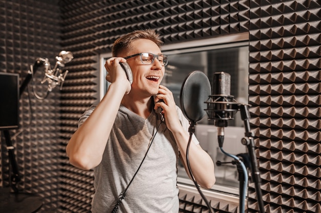 Der Sänger singt im Studio in ein Mikrofon. Mann mit Kopfhörer schreibt einen Podcast, ein Hörbuch. Künstler, der ein Album aufnimmt, mit dem Label arbeitet. Ansager nimmt eine Rede bei einem Radiosender auf