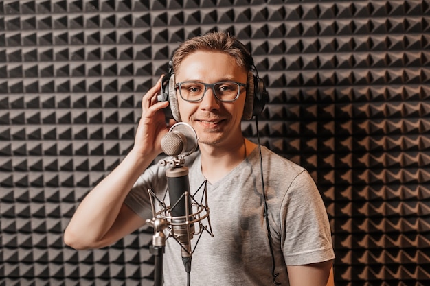 Der Sänger singt im Studio in ein Mikrofon. Mann mit Kopfhörer schreibt einen Podcast, ein Hörbuch. Künstler, der ein Album aufnimmt, mit dem Label arbeitet. Ansager nimmt eine Rede bei einem Radiosender auf