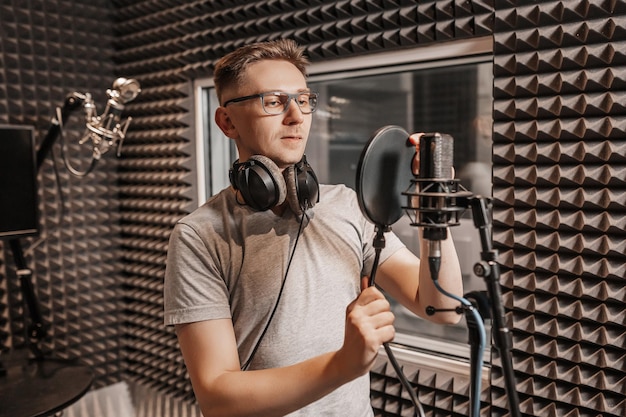 Der Sänger singt im Studio in ein Mikrofon. Mann mit Kopfhörern schreibt einen Podcast, ein Hörbuch. Künstler, der ein Album aufnimmt, mit dem Label arbeitet. Ansager nimmt eine Rede bei einem Radiosender auf