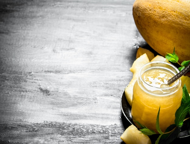 Der Saft aus der Melone mit den Minzblättern. Auf dem schwarzen Holztisch.