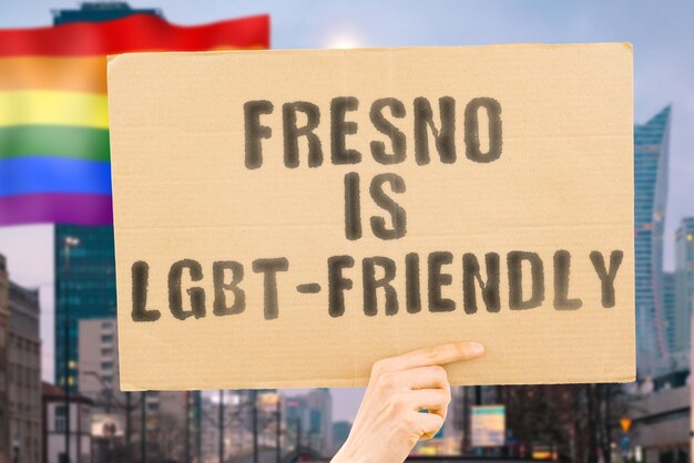 Der Satz "Fresno ist LGBT-freundlich" auf einem Banner in Männerhand mit verschwommener LGBT-Flagge im Hintergrund. Menschlichen Beziehungen. unterschiedlich. Vielfältig. Freiheit. Sexualität. Soziale Fragen. Gesellschaft