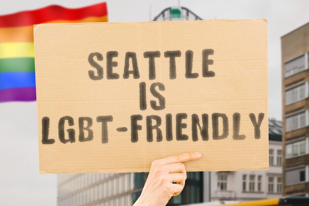 Der Satz „Seattle ist LGBT-freundlich“ auf einem Banner in Männerhand mit unscharfer LGBT-Flagge im Hintergrund. Menschlichen Beziehungen. unterschiedlich. Vielfältig. Freiheit. Sexualität. Soziale Fragen. Gesellschaft