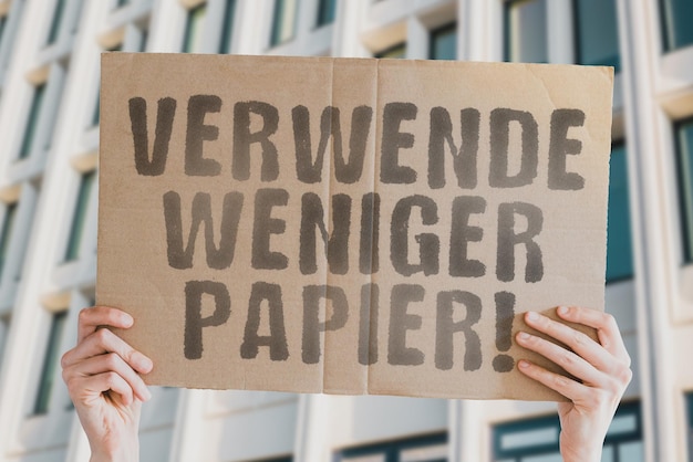 Der Satz Verwenden Sie weniger Papier auf einem Banner in Männerhand mit verschwommenem Hintergrund Menschliche Auswirkungen auf die Umwelt Umweltzerstörung Natur Wald Bäume Moderne Technologie