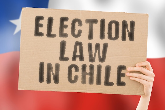 Der Satz Wahlgesetz in Chile auf einem Banner in Männerhänden mit einer verschwommenen chilenischen Flagge im Hintergrund Verfassung Politischer Senat Santiago Wählermehrheit