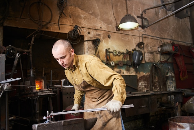 Der Schmied bei der Herstellung von Kunsthandwerk aus Metall auf dem Amboss in der Werkstatt