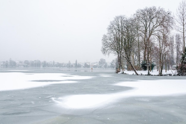 Der Schnee fällt auf die kahlen Bäume und den zugefrorenen See von Enghien-les-Bains