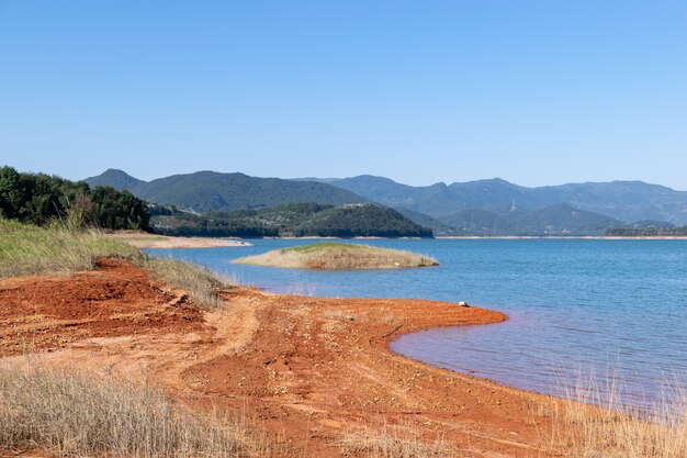 Der See unter blauem Himmel hat blaues Wasser und rotes Land