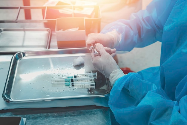 Foto der selektive fokus auf die hand des arztes zieht eine medizinische flüssigkeit in die nadelspritze für die patientenimpfung im krankenhaus