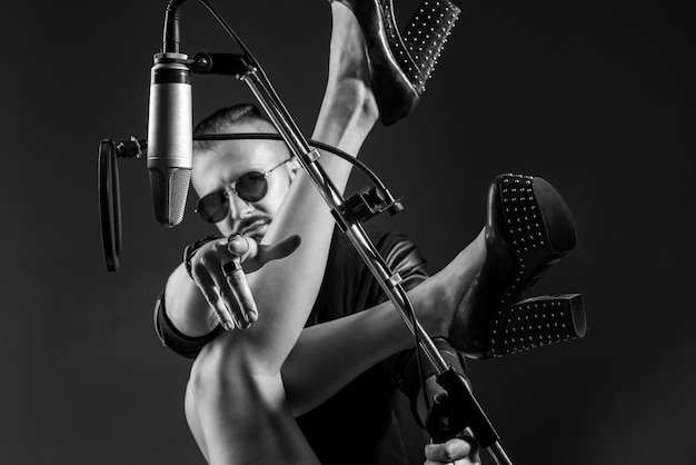 Der sexy Sänger DJ spielt einen Rocksong mit einem Mikrofon, während er ihn in einem Musikstudio aufnimmt