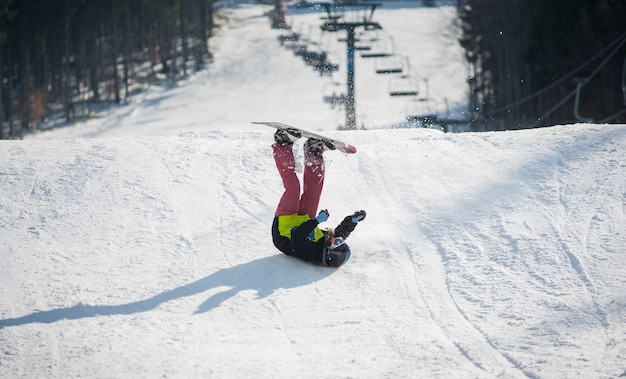 Der Snowboarder fällt während der Abfahrt auf die Piste