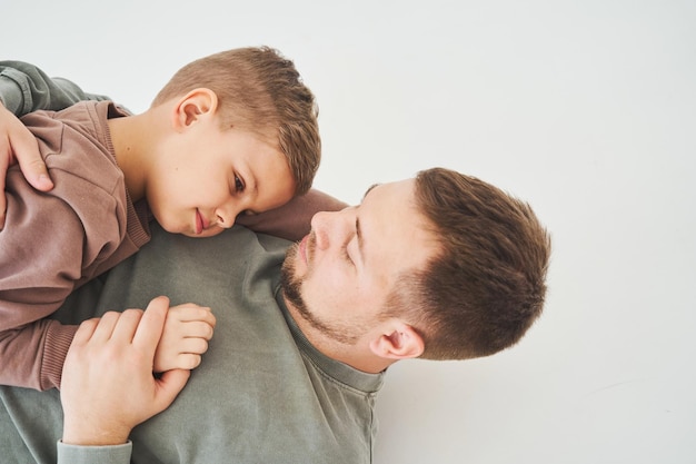 Der Sohn liegt auf der Schulter seines Vaters Papa umarmt sein Kind und lächelt Kinderbetreuung