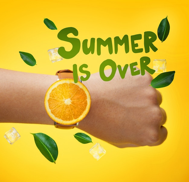 Der Sommer ist vorbei Typografie. Männliche Hand, die Frucht-orange Uhr-Grün-Blätter trägt