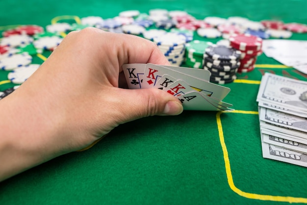 Der Spieler zeigt mehrere Spielkarten auf einem grünen Tisch in einem Casino mit Chips-Glücksspiel