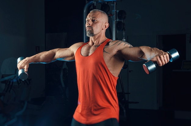 Der starke muskulöse Mann trainiert im Fitnessstudio