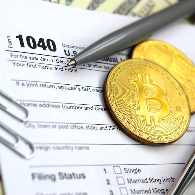 Der Stift, Bitcoins und Dollarnoten liegen auf dem Steuerformular 1040 US