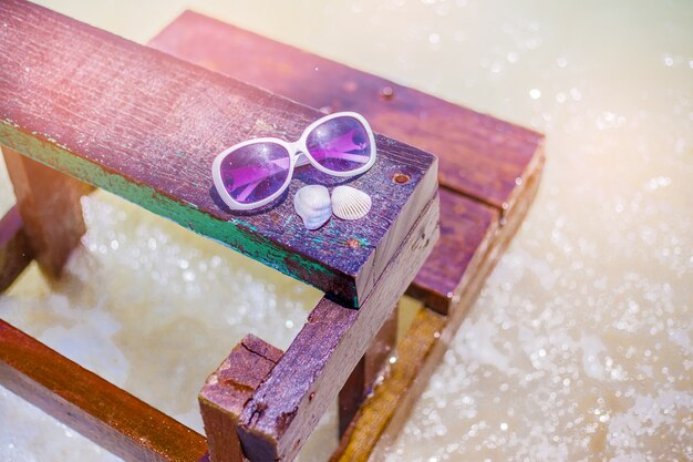 Der Strand mit Sonnenbrille auf dem hölzernen