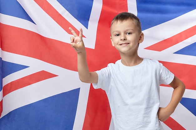 Der süße Junge faltete seine Finger in Form eines V gegen die britische Flagge