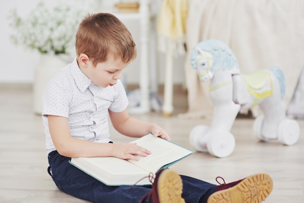 Der süße kleine Junge geht zum ersten Mal zur Schule. Kind mit Tasche und Buch. Kind macht eine Aktentasche, Kinderzimmer auf einem Hintergrund