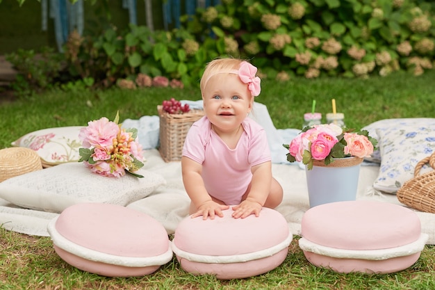 Der Tag der Kinder, ein Kindermädchen im Park sitzt in einem Korb mit Makronen auf einem Sommerpicknick