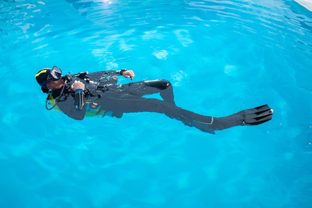 Der Taucher schwimmt auf dem Rücken im Pool