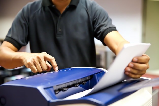 Der Techniker drückt die Taste von Hand und legt Papier in das Fach ein, um den Fotokopierer zum Scannen von Faxen oder Fotokopien zu verwenden oder Dokumente zu kopieren, nachdem der Papierstau behoben oder die Tonerkartusche am Büroarbeitsplatz gewechselt wurde
