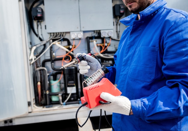 Der Techniker repariert elektronische Temperatursensoren mit einem elektronischen Lötkolben