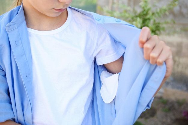 Der Teenager zeigt einen Schweißstreifen an den Achseln des Hemdes