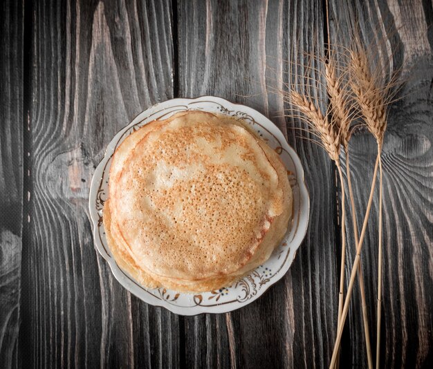 Der Teller mit Pfannkuchen und Ohr ist auf einem Holztisch isoliert. Das Konzept von Maslenitsa. Selektiver Fokus.