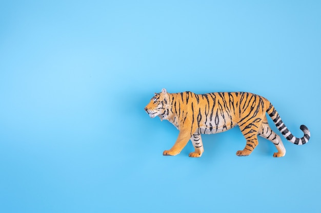 Der Tiger, Symbol des Jahres 2022. Kunststoff orange Spielzeugfigur Tiger auf blauem Grund. Ansicht von oben. Platz für Text