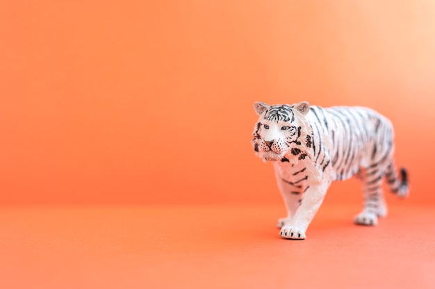 Der Tiger, Symbol des Jahres 2022. Kunststoff weiße Spielzeugfigur Tiger auf rotem Grund. Platz für Text