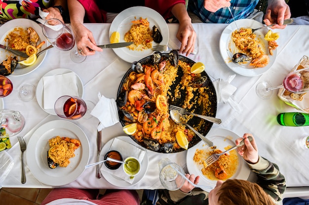 Der Tisch im Restaurant mit spanischer Paella mit Meeresfrüchten wird in einer Pfanne serviert. Frische Garnelen, Scampi, Muscheln, Tintenfisch, Tintenfisch und Jakobsmuscheln. Draufsicht. Restaurant