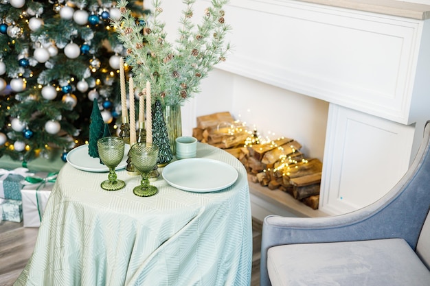 Der Tisch ist in der Nähe des Weihnachtsbaums für ein romantisches Silvesterdinner Festliches Silvesterdinner gedeckt
