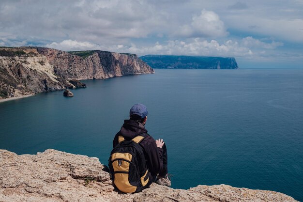 Der Tourist macht auf dem Smartphone ein Foto von einer unglaublich malerischen Aussicht von einer Klippe auf dem Meer