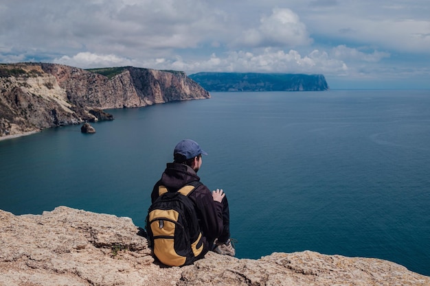 Der Tourist macht auf dem Smartphone ein Foto von einer unglaublich malerischen Aussicht von einer Klippe auf dem Meer