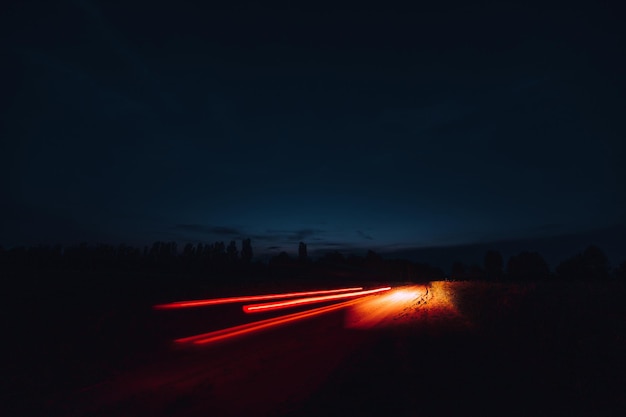 Der Trail der Autolichter mit langer Belichtungszeit im Feld in der Nacht