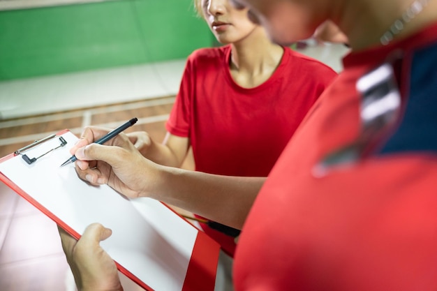 Der Trainer gibt den Spielern Anweisungen, die Stift und Klemmbrett verwenden