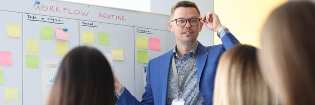 Der Trainer im Büro, der an der Tafel steht, unterrichtet Frauen