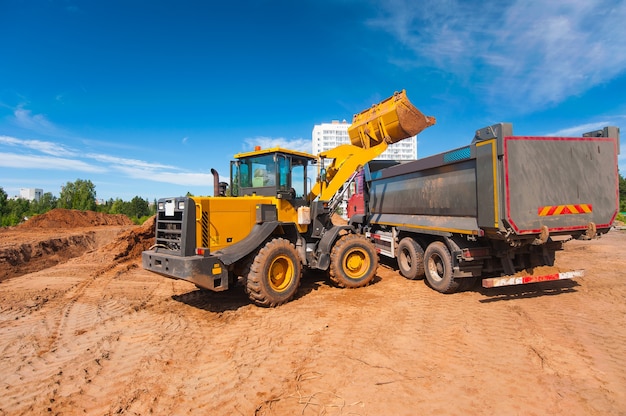 der Traktor lädt den Boden in den Muldenkipper Straßenreparaturen