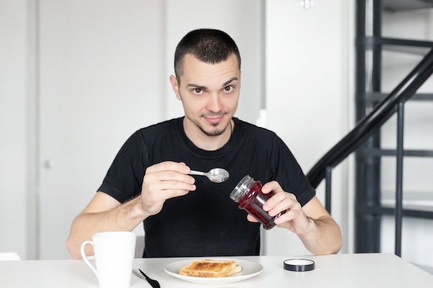 Der Typ frühstückt mit Toast mit Marmelade.