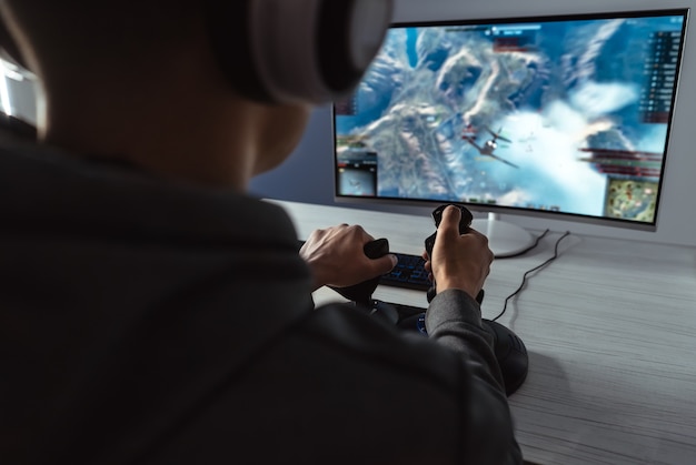 Der Typ-Gamer mit Headset, der Videospiele auf seinem PC spielt