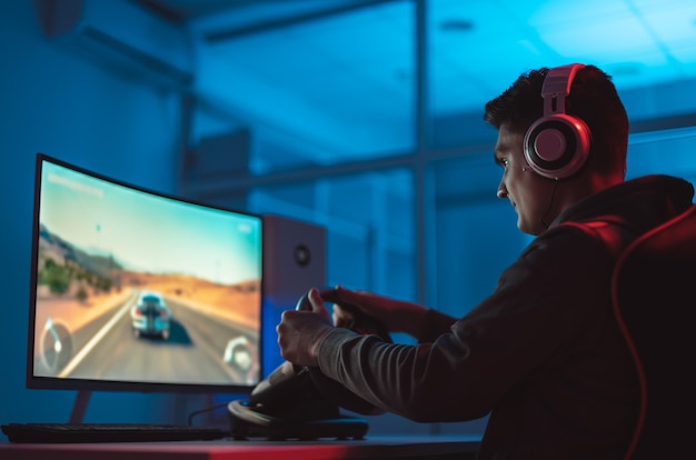 Der Typ-Gamer mit Headset, der Videospiele auf seinem PC spielt