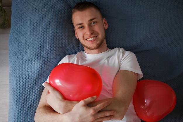 Der Typ hält einen Ballon in Form eines Herzens zum Valentinstag