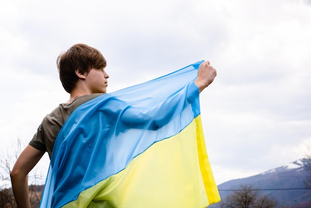 Der Typ hat die ukrainische Flagge vor dem Hintergrund des Himmels gestreckt