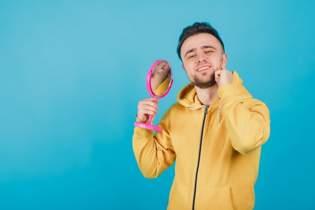 der typ im gelben sweatshirt betrachtet sich im rosa spiegel