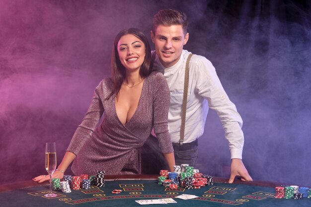 Der Typ im weißen Hemd spielt Poker im Casino am Tisch mit Stapeln von Chips darauf, er feiert den Sieg