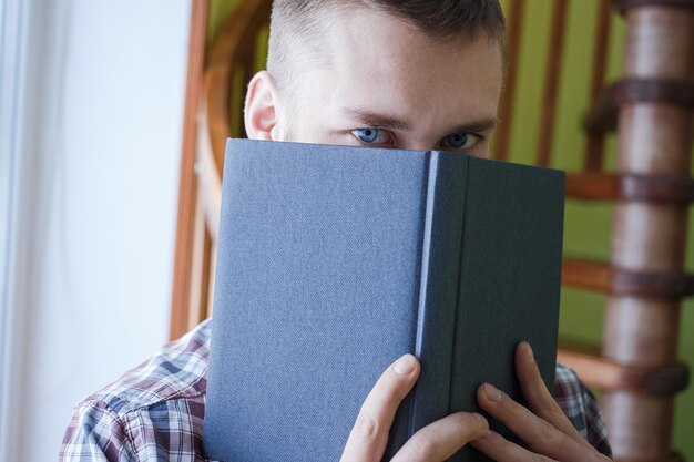 Der Typ in einem karierten Hemd bedeckte sein Gesicht mit einem Notizbuch
