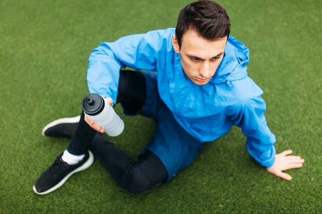 Der Typ ruht sich nach einem guten Training aus. Kerl nach dem Training, Trinkwasser auf dem Fußballplatz. Porträt des schönen Kerls in der Sportbekleidung.