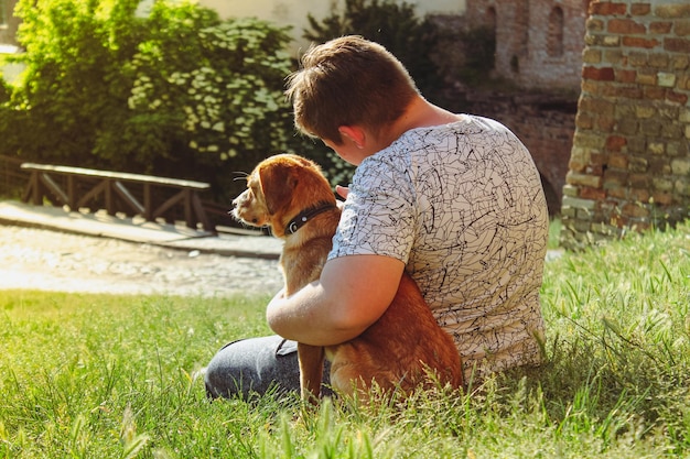 Foto der typ sitzt mit dem hund im gras