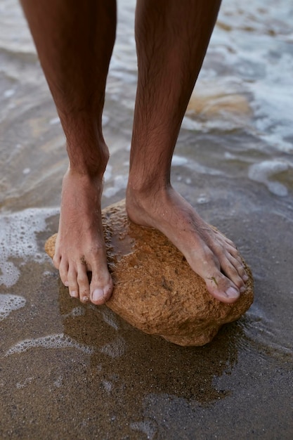 Der Typ steht barfüßig im Sand, Füße aus nächster Nähe